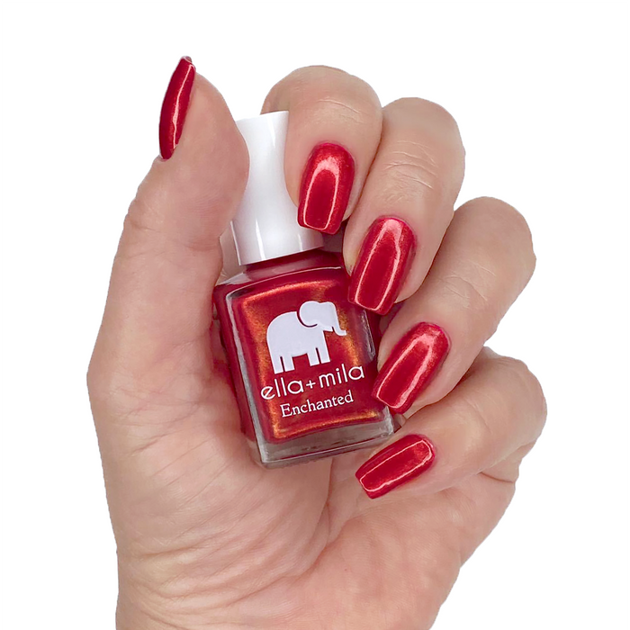 Poison Apple red golden shimmer nail polish manicure on a light skin tone with the bottle