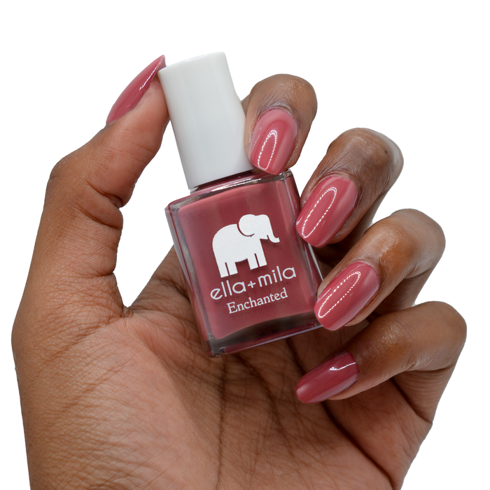Rise of Petals berry burgundy nail polish on a deep skin tone, hand holding the bottle